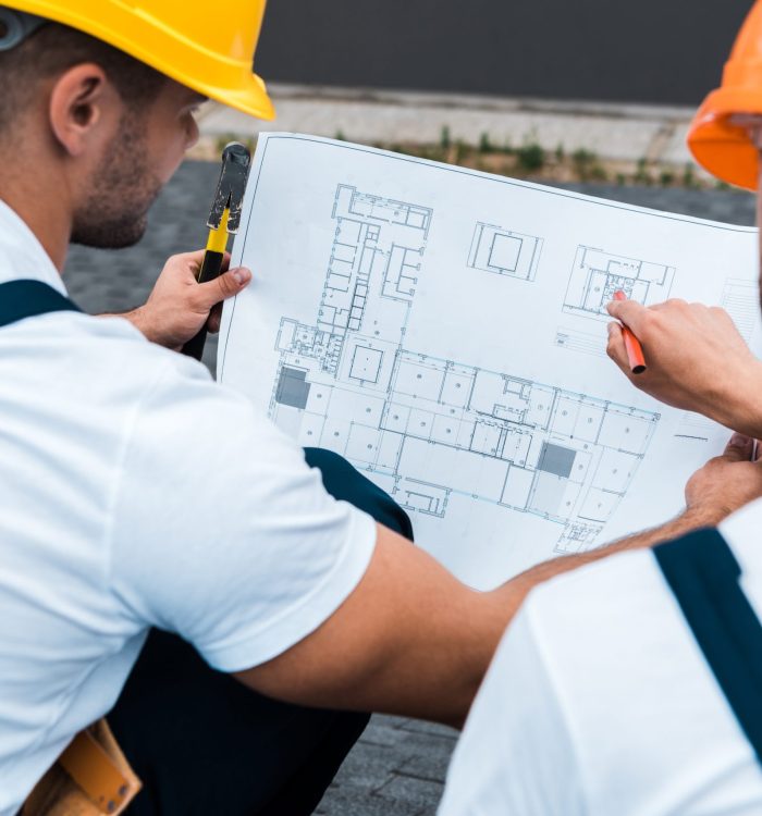 selective focus of builders in helmets looking at blueprint selective focus of builders in helmets looking at blueprint